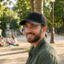 Homme souriant portant une casquette en coton fabriquée en France dans un parc.